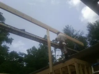 Carpenter setting a ridge beam over a new addition frame — Ice Dam Removal by Roofing Brothers in Masonville