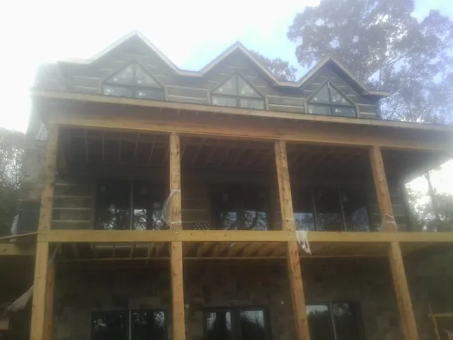 Dormers and porch framing on a large log home under construction — Roof Coating work by our crew in Masonville