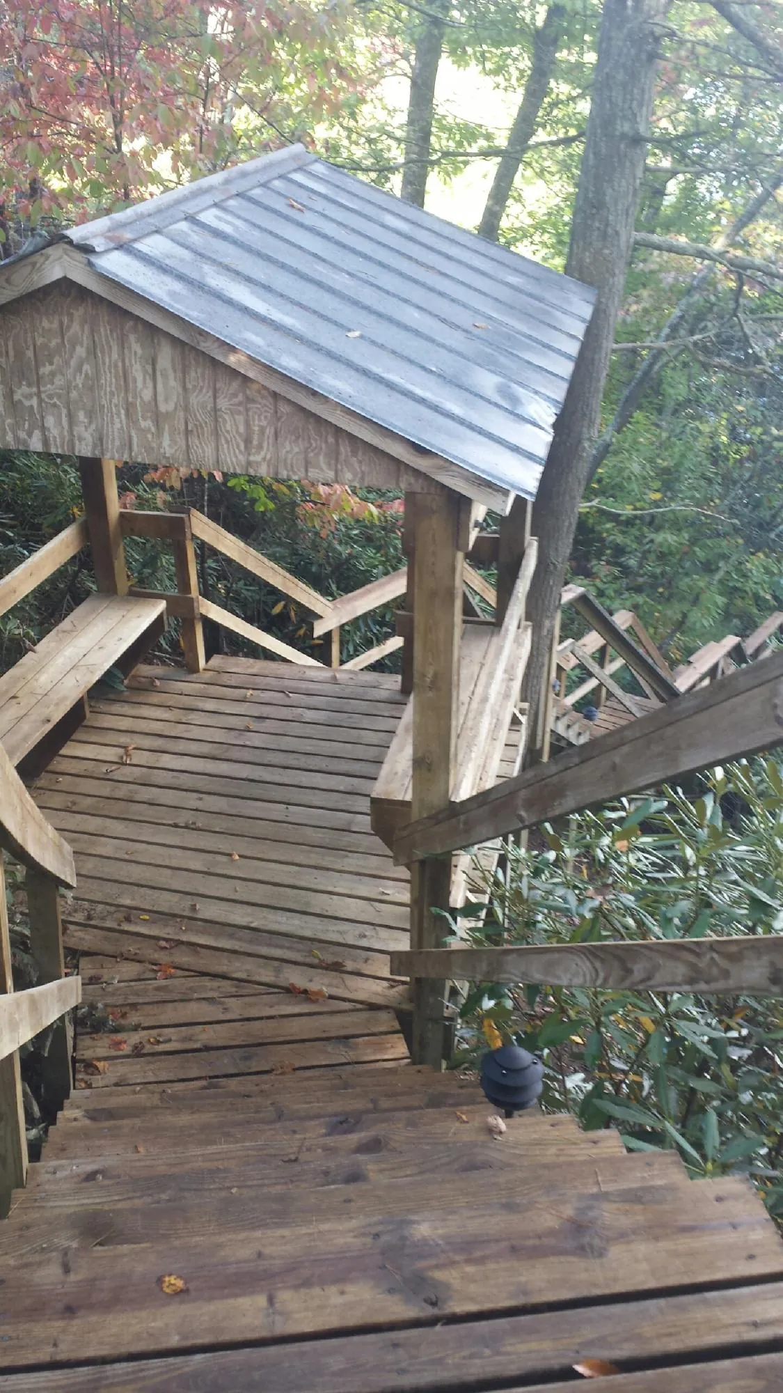Metal roofed shelter over wooden steps on a wooded walkway — Skylight Repair & Installation work by our crew in Masonville